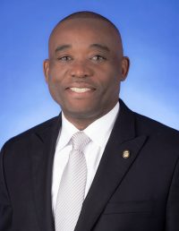 headshot of Commissioner Monestime in a dark suit and white tie