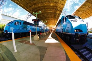 2 blue Tri-Rail trains on a railroad track at a stop